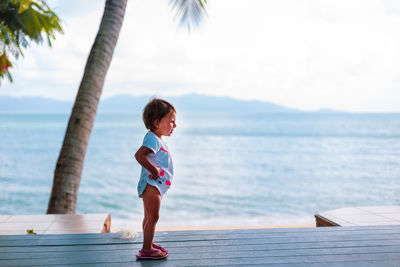 Full length of girl standing against sea