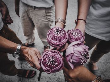 Midsection of people holding lotuses