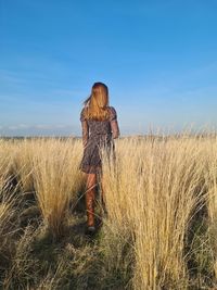 Rear view of woman standing on field against sky