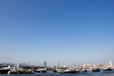 Boats moored in sea against clear blue sky