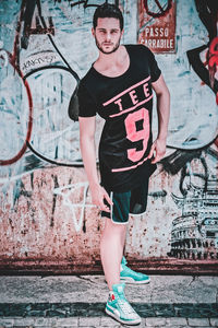 Portrait of teenage girl standing against graffiti wall