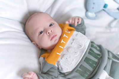 Close-up of cute baby girl lying on bed