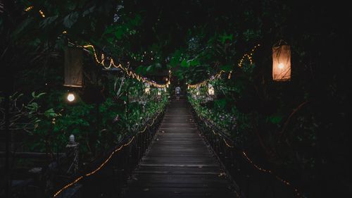 Illuminated lights over footbridge at night