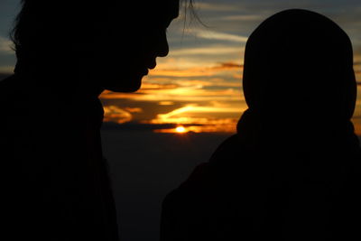 Close-up portrait of silhouette people against sky during sunset