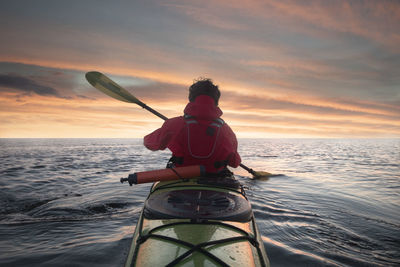 A man is kayaking in the open sea. back view