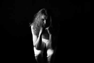 Young woman wearing mask against black background