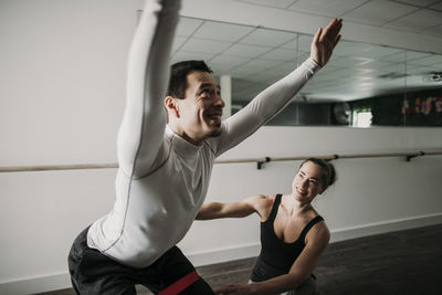 Male does squats as his female personal trainer looks on and coaches