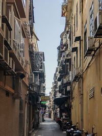 Narrow street amidst buildings against sky in city