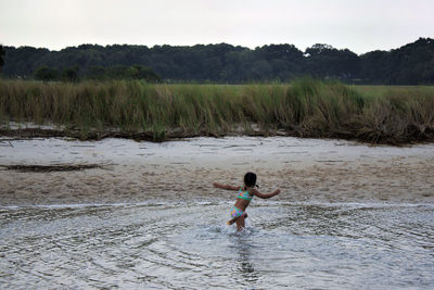 Rear view of girl running in water at beach