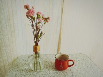 Flower vase on table against wall at home