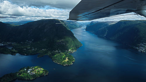 Scenic view of sea by mountain against sky