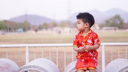 Cute boy looking away while sitting outdoors