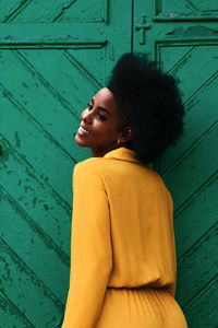 Side view of smiling young woman looking away against wall