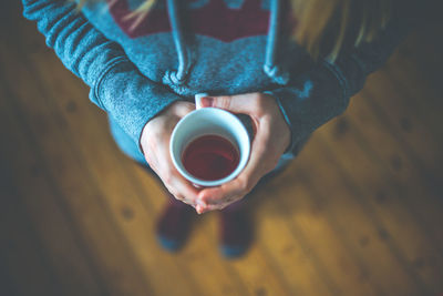 Low section of woman holding coffee cup on table