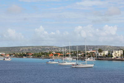 Sailboats moored on sea against sky in city