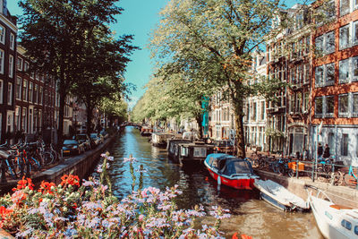 Boats moored in canal amidst buildings in city