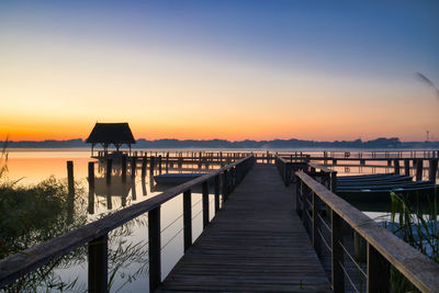 Pier over lake against sky during sunset