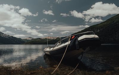 Sailboats moored on lake against sky