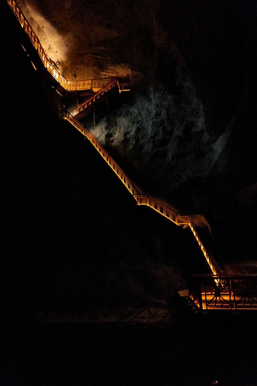 LOW ANGLE VIEW OF ILLUMINATED FACTORY AT NIGHT