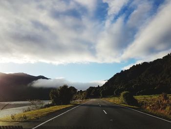 Road by mountains against sky