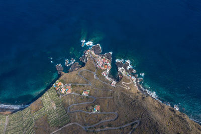 Aerial view at fissured coastline serpentine road and houses at shoreline of canary island