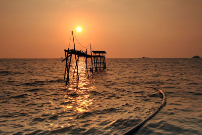 Silhouette ship in sea against clear sky during sunset