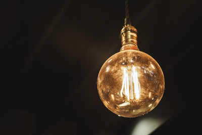 Low angle view of illuminated light bulb in darkroom