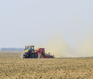 Tractor on agricultural field against clear sky