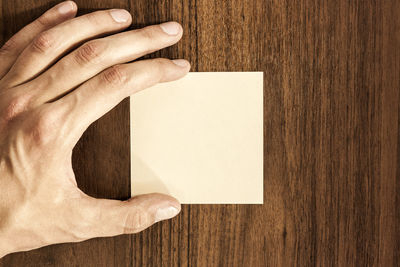 Directly above shot of man holding paper on table