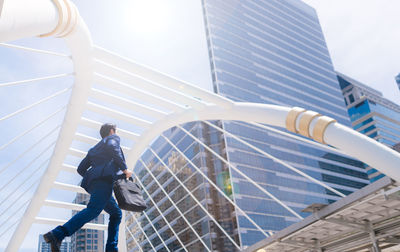 Low angle view of businessman moving on steps against buildings in city