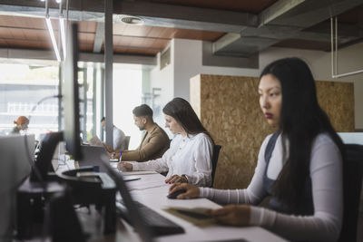 Group of focused multiracial colleagues siting at table and working on project in modern coworking space