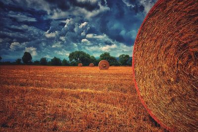 Hay bales on field against sky