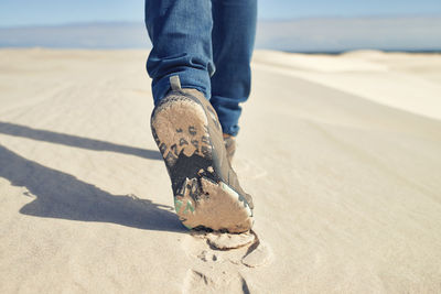 Low section of man standing on sand at beach