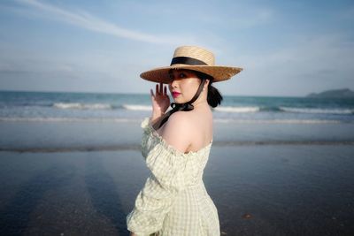 Young woman wearing hat while standing on beach