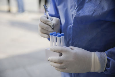 Midsection of scientist holding test tubes