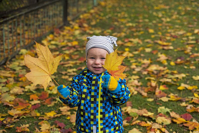 Portrait of happy boy standing on autumn leaves