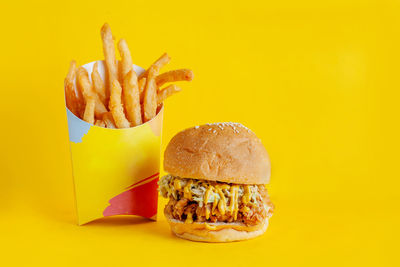 Close-up of burger on table against yellow background