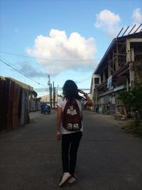 Rear view of woman walking in city against sky