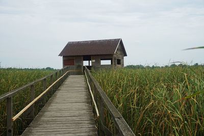 Wooden house on field against sky