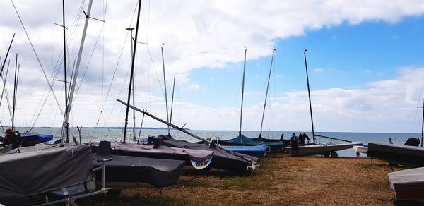 Sailboats moored in sea against sky