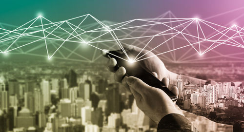 Digital composite image of hand against illuminated buildings in city at night