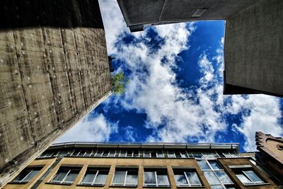 View vertically up to the blue sky and white clouds between buildings