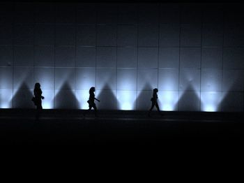 Silhouette people standing against illuminated wall