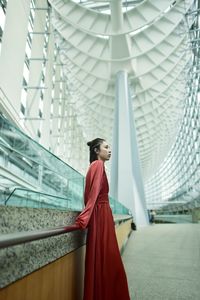 Portrait of young woman standing against building