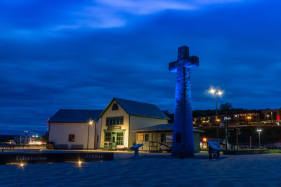 Illuminated buildings against blue sky at night