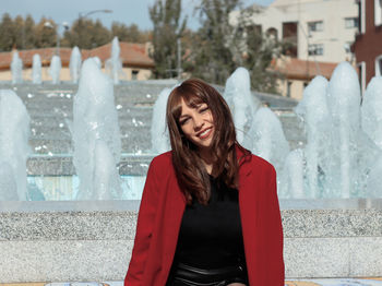 Portrait of smiling woman sitting against fountain