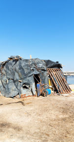 Damaged boat on beach against clear blue sky