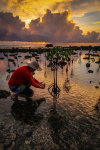 Man at beach against sky during sunset