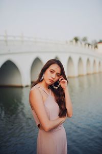 Portrait of young woman standing by lake