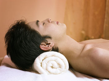High angle view of shirtless man lying down on massage table